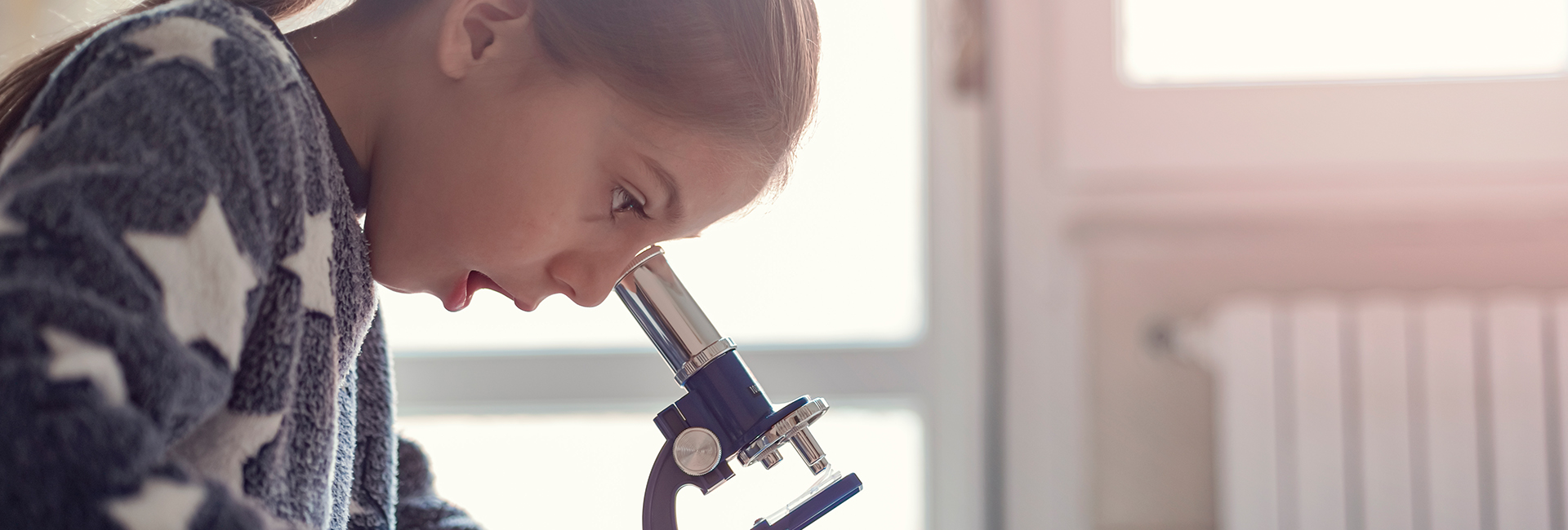 Little girl looking into a microscope