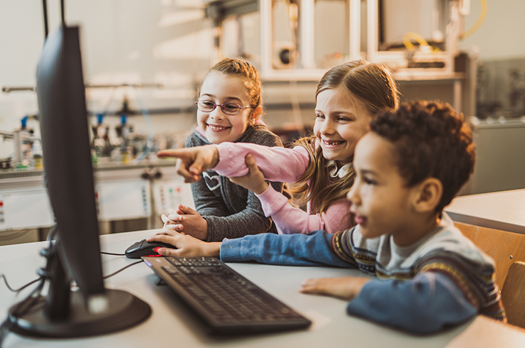 Three kids looking at a computer and working together